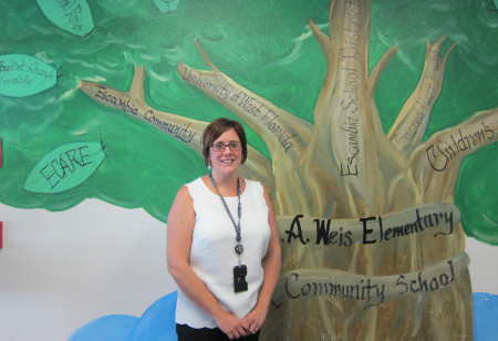 Holly Magee, principal at C.A. Weis Elementary School, in front the community tree highlighting partners with the school in the Community School project to offer wraparound services to Weis' families. Credit: Shannon Nickinson.