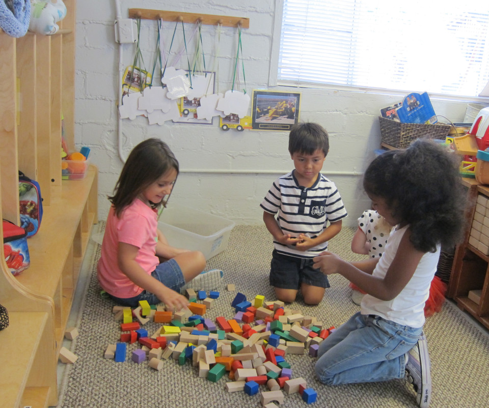 Three children sitting on the floor playing with blocks