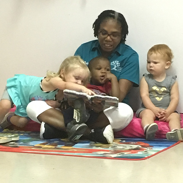 Teacher reading a book to three children
