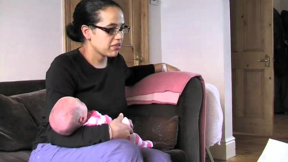 Woman sitting on couch holding baby