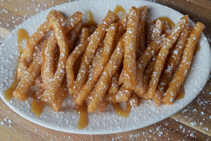Funnel Cake Sticks coated with powered sugar and syrup