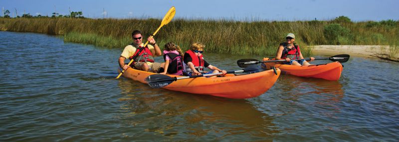 group in orange kayak on water with fishing pole