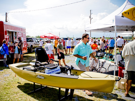 Green kayak in booth at outdoor festival with crowd