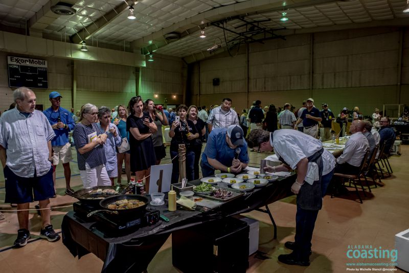 crowd of people in front of food booth while chef cooks in convention hall