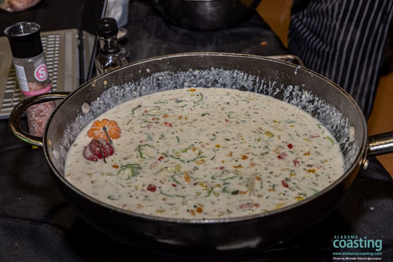 big wok filled with cream-based soup and colorful chopped vegetables