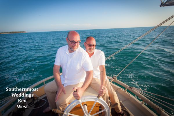 Wedding couple steer the sailboat after their beach wedding by Southernmost Weddings Key West