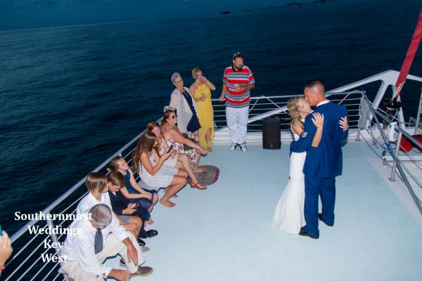 Wedding couple dances on the deck of a large stable catamaran during their sunset sail wedding reception