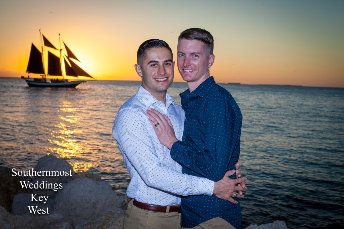 Two men kiss under a rainbow flag after their wedding y Southernmost Weddings Key West