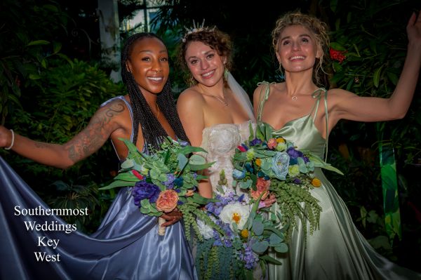 A bride poses with her bridesmaids in a tropical garden after her wedding