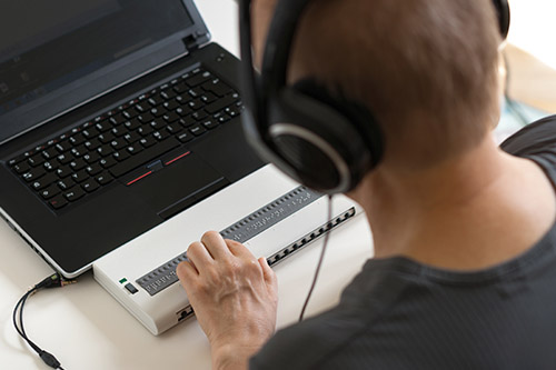 Image of a blind man typing on a computer keyboard