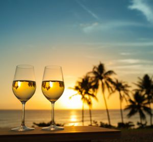 Two wine glasses on a railing overlooking the ocean