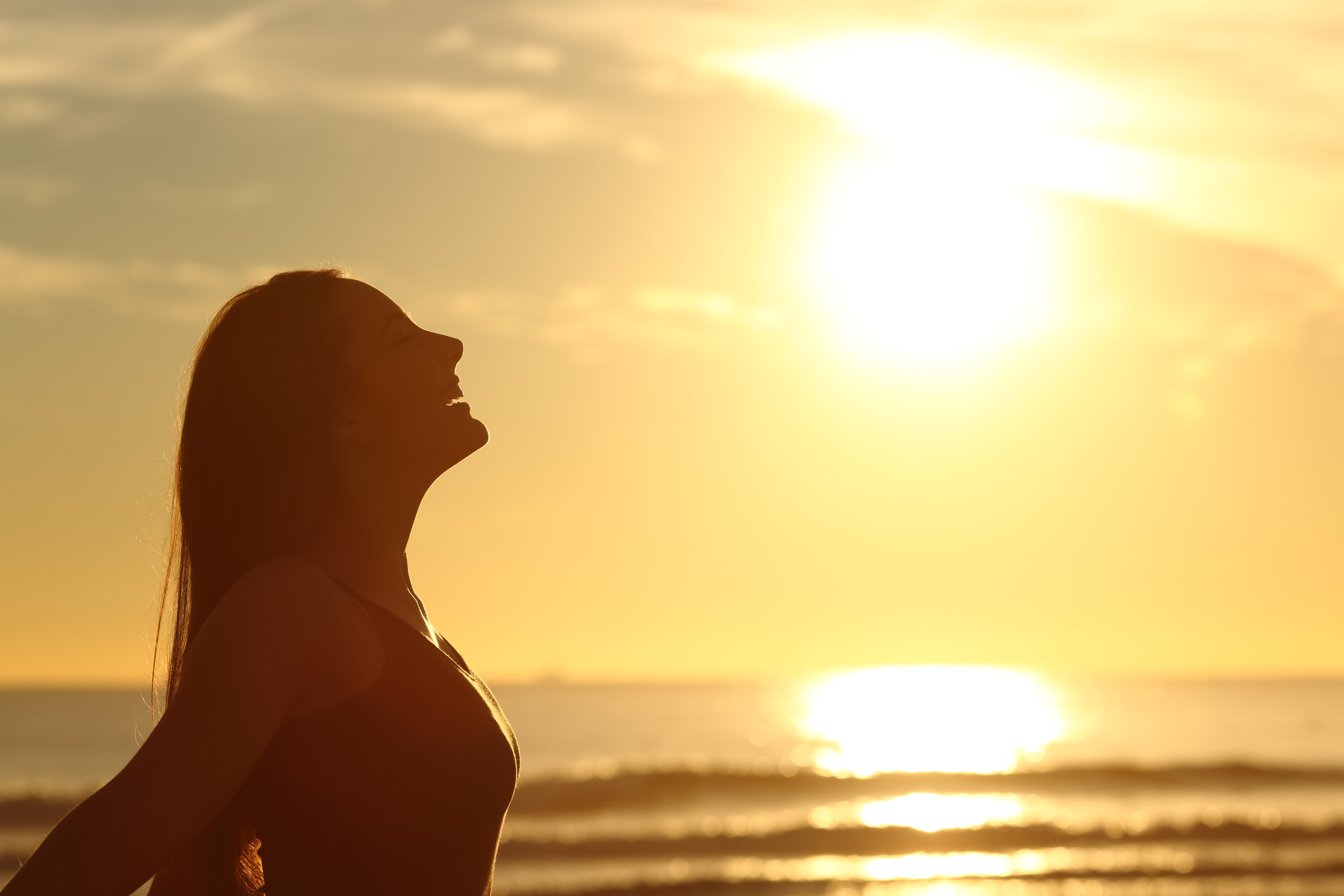 profile of woman standing with sun on her face at the beach