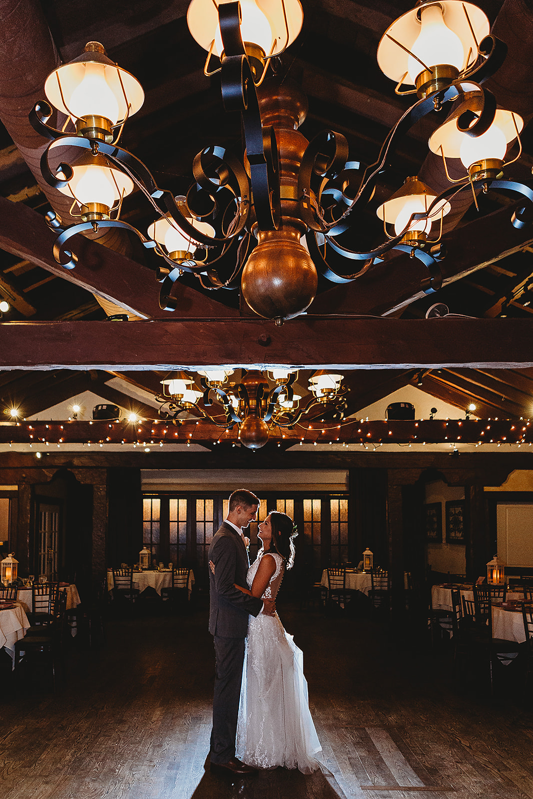 bride and groom kiss on the dance floor under dimmed lighting