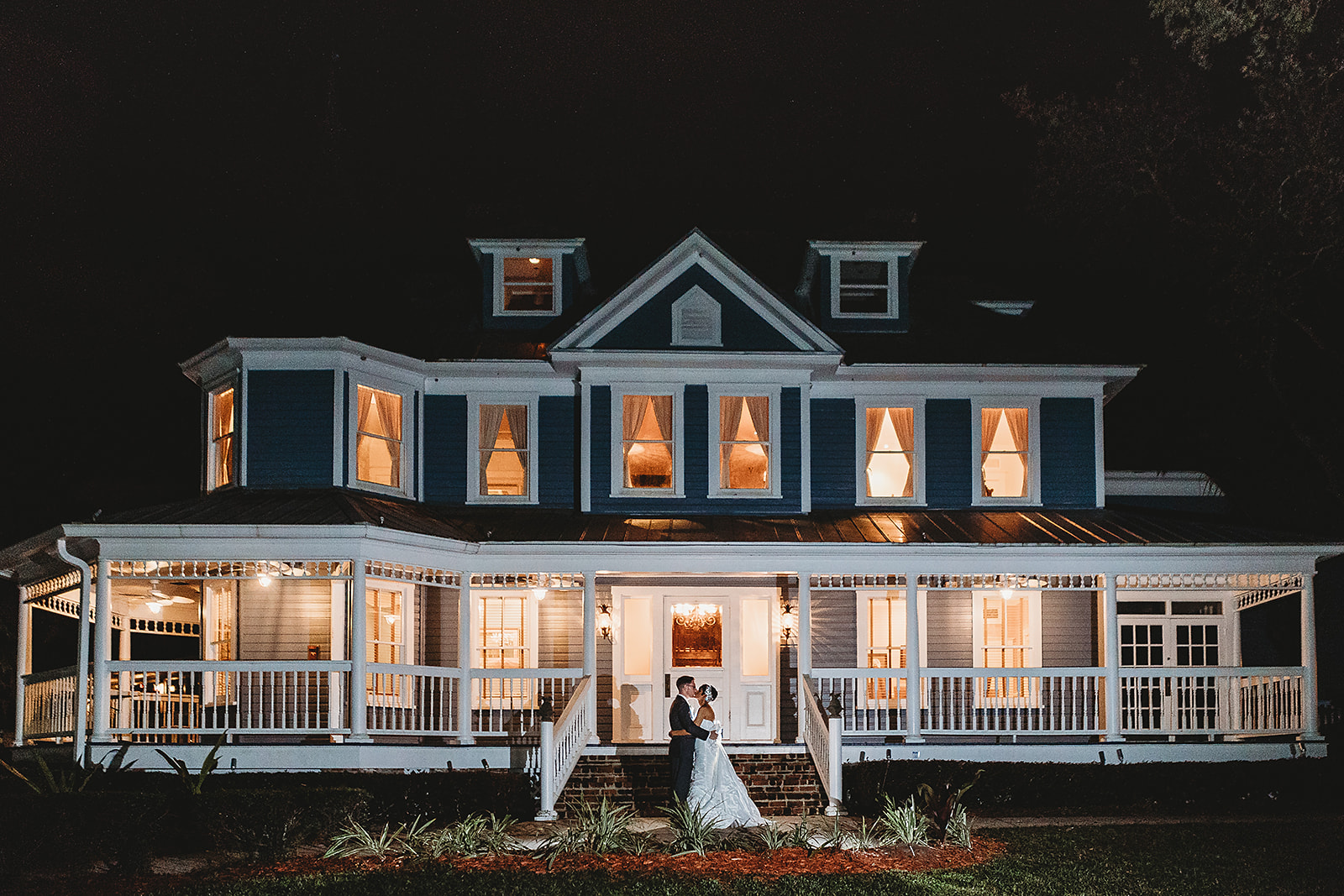 bride and bridesmaid posing in front of highland manor at night