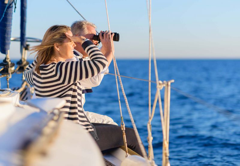 Couple on a sailboat looking through binoculars