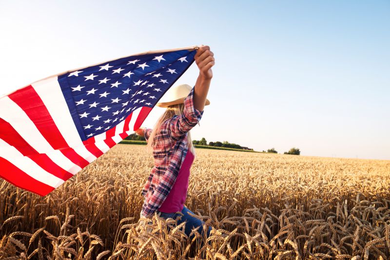 Image of woman in wheat field with American Flag